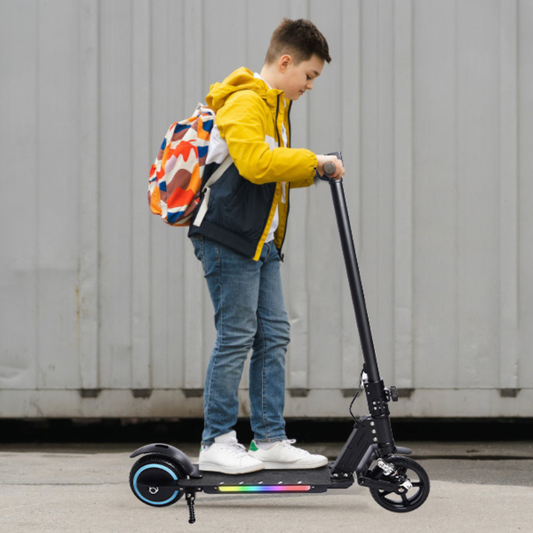 Child on a scooter with a colorful backpack against a plain background